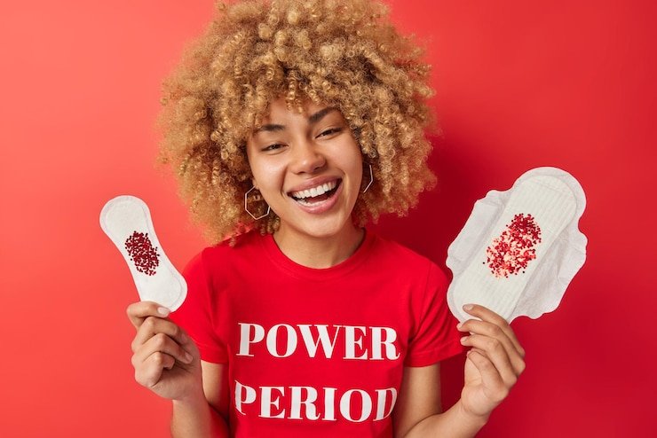 cheerful-woman-with-curly-bushy-hair-holds-organic-gaskets-made-bio-cotton-laughs-positively-dressed-casual-t-shirt-with-inscription-isolated-vivid-red-background-hygiene-concept_273609-62497